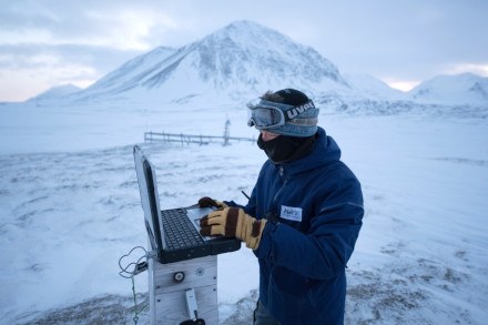 A researcher in the arctic working on a laptop